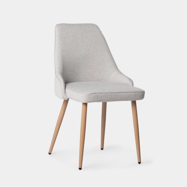 Aporta un toque de elegancia y confort a tu comedor con la silla Nika. Esta pieza combina un tapizado suave en color gris con patas metálicas efecto madera